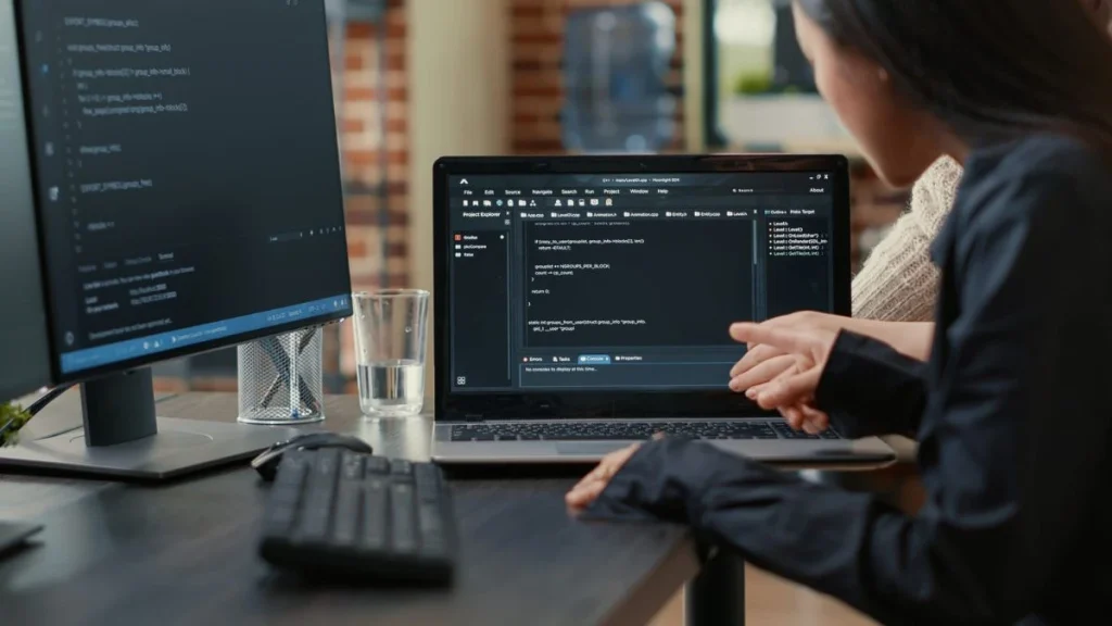 Duas pessoas discutindo programação em frente a dois monitores de computador.